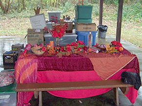 Red cloth, red decorations on table in front of piled-up boxes and tubs.