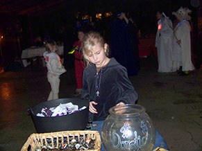 Young girl concentrates on supervising small cauldron, basket, fishbowl on welcome table.