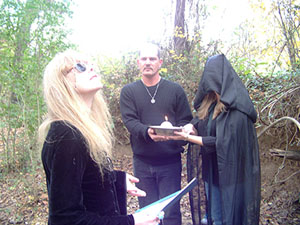 High Priestess invokes the Gods while handfasting man with candle, woman in veil.