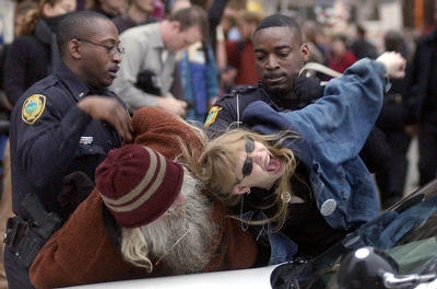 Tortilla Dave and Lady Passion, screaming in pain, as two policeman twist their arms and hold them down on a police-car hood